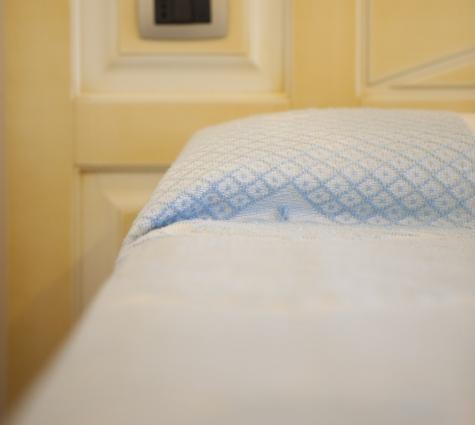 Asciugamano blu su letto, sfondo chiaro.