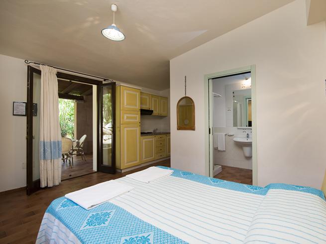 Camera da letto con cucina, armadio e accesso al giardino.