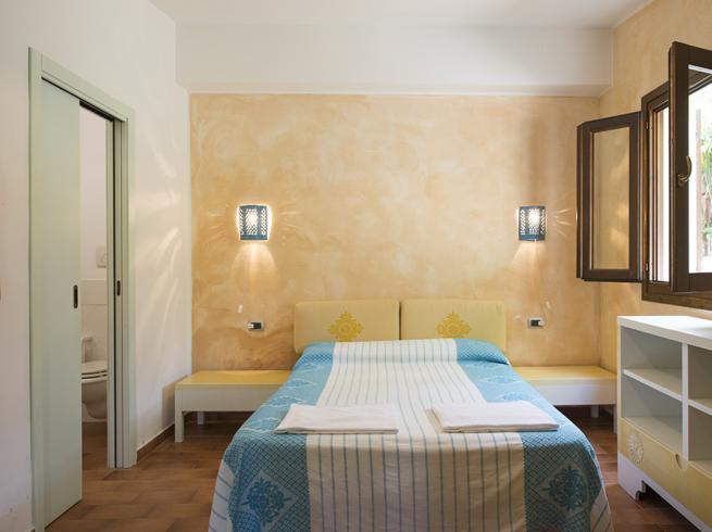 Camera luminosa con letto matrimoniale, bagno privato e finestra aperta.