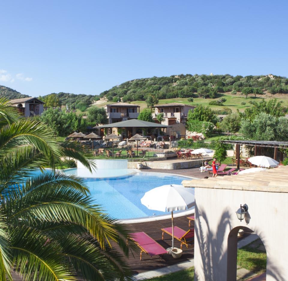 Resort con piscina e vista collinare, ombrelloni e lettini.